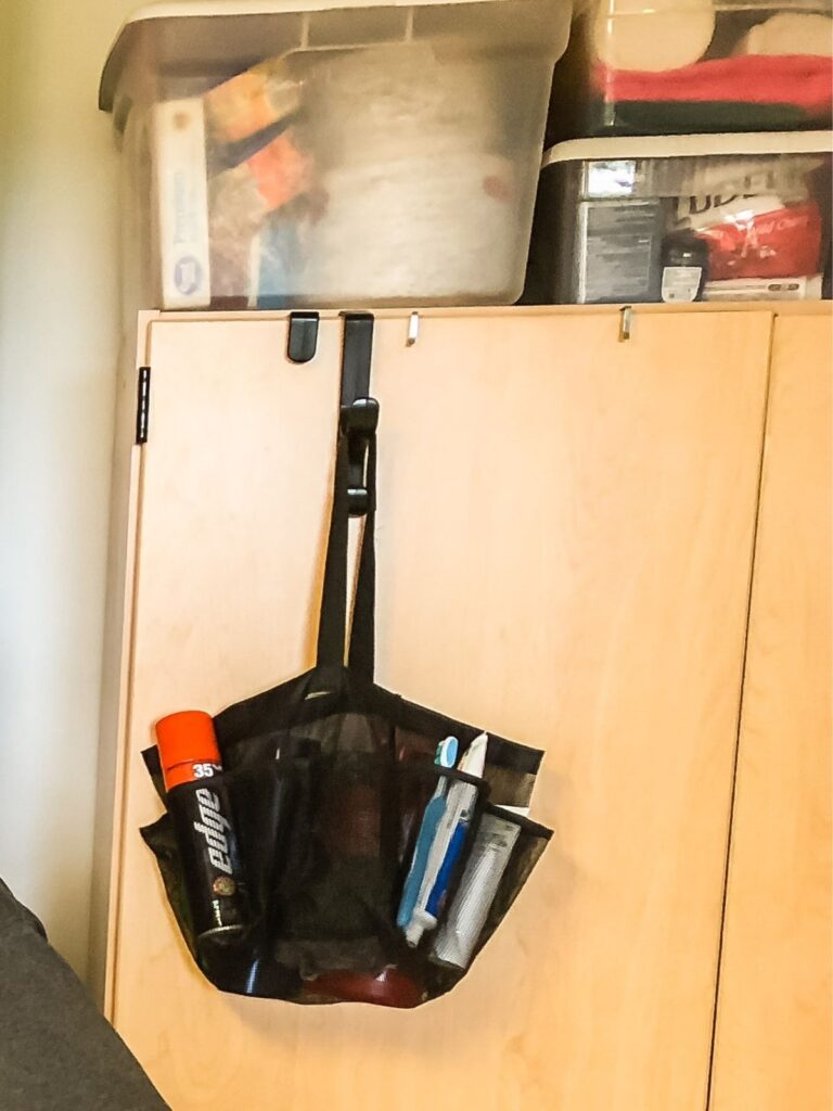 Black shower caddy hanging on closet door filled with toiletries