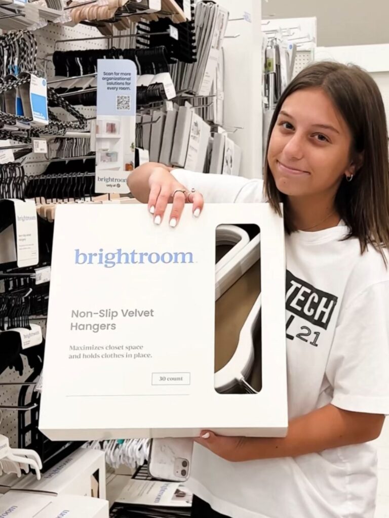 Student holding package of Brightroom non-slip velvet hangers in store aisle with organization products