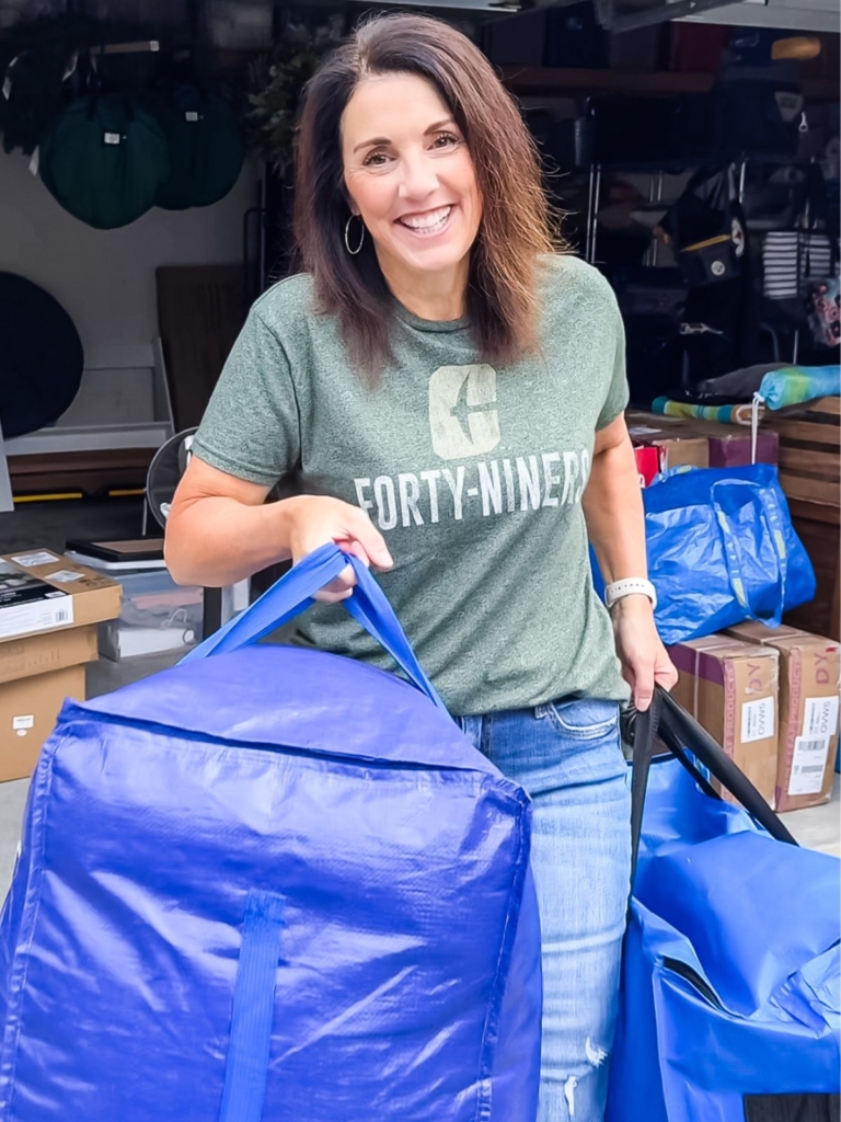 Mom carrying large heavy-duty moving bags filled with dorm belongings during move-out.